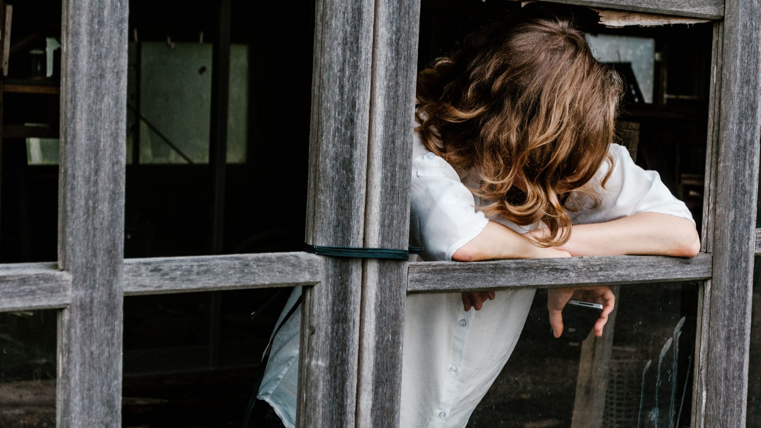"Girl standing at the window of a barn, expressing anxiety"