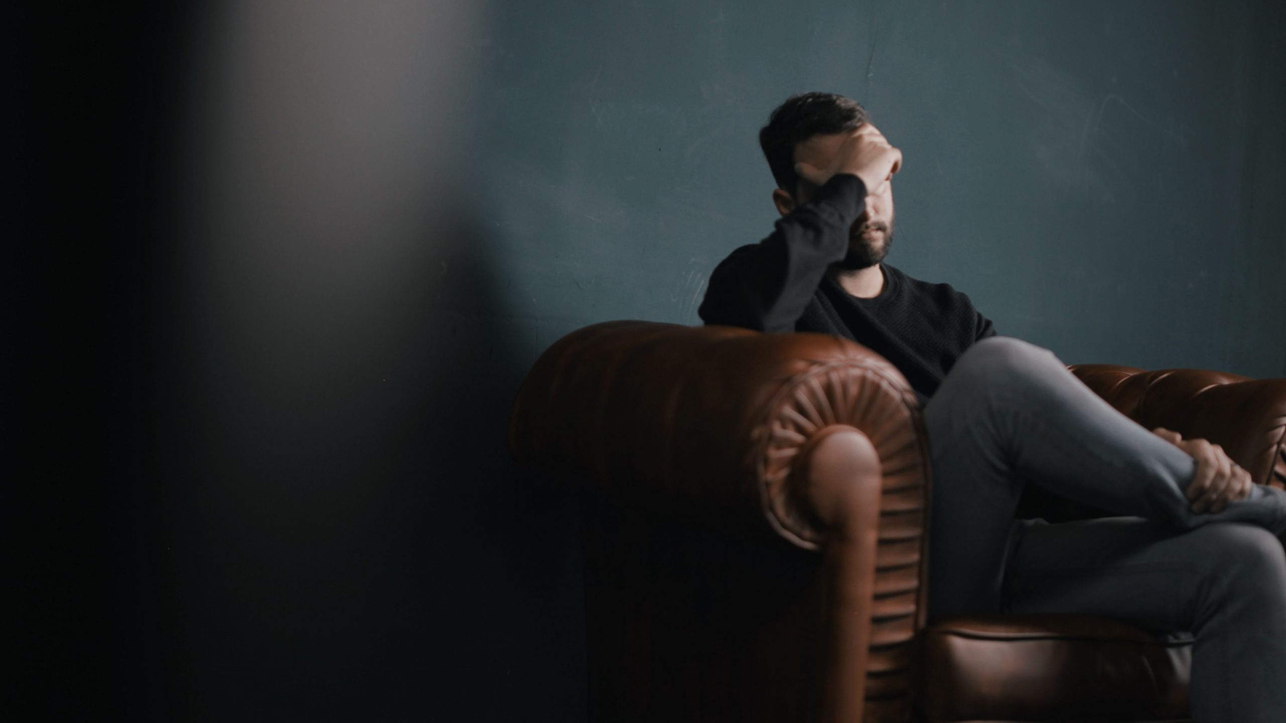 "Man sitting on couch feeling anxious"